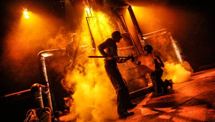 attore in scena tra fumo e luci che sembrano fiamme