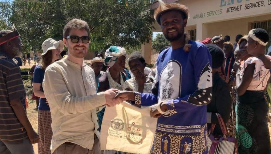 un rappresentante della federico II regala una borsa con lo stemma sinapsi ad un indigeno