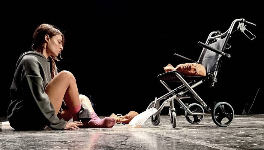 attrice in scena con una sedia a rotelle